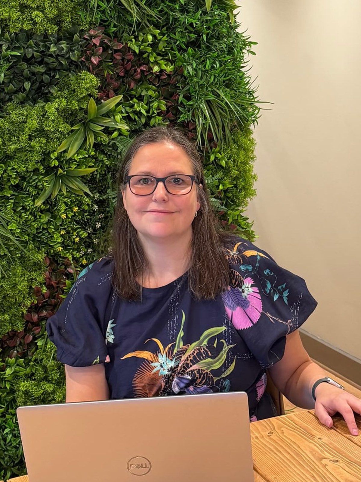 Amanda Weekes working at a laptop in front of a living green wall